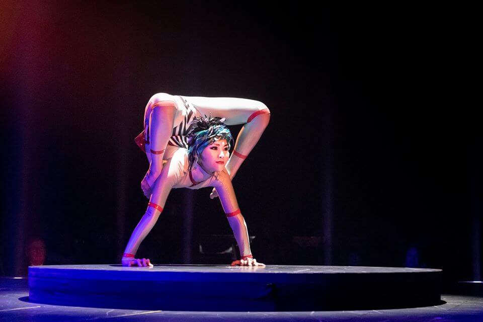Cirque du Soleil performer doing handstand with legs wrapped around shoulders in backbend