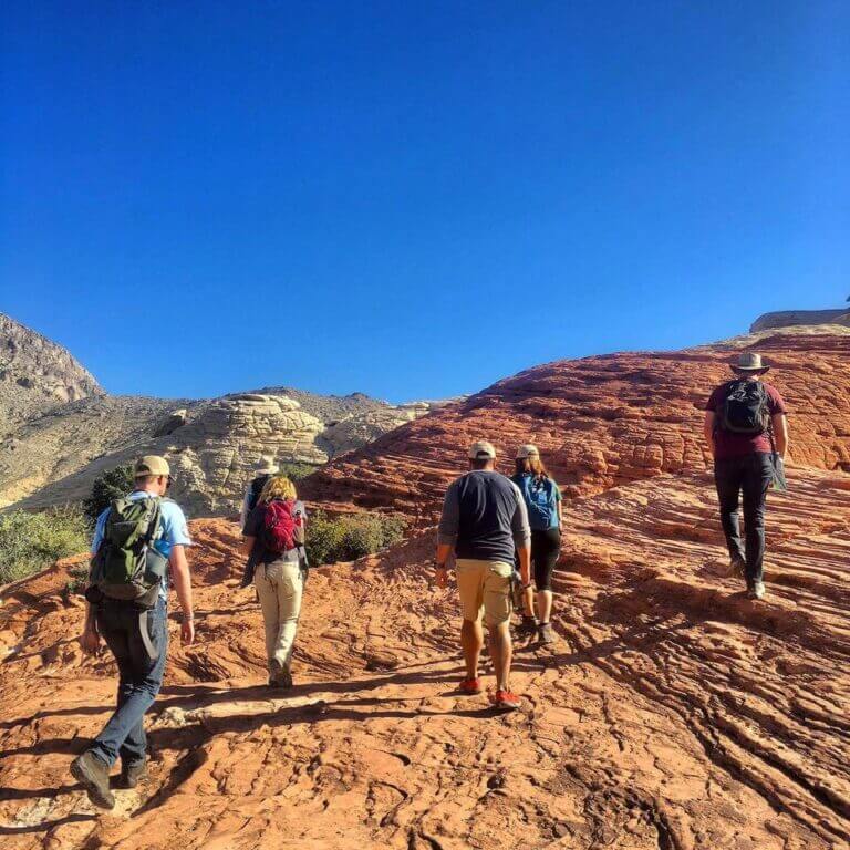 hikers walk up desert canyon hill
