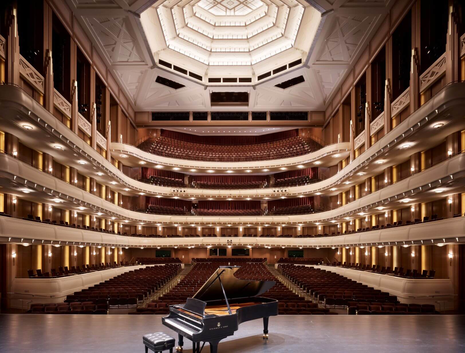 piano sits on stage of grand performance hall