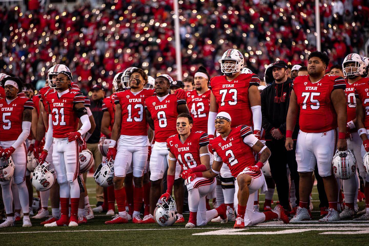 football players stand on sideline