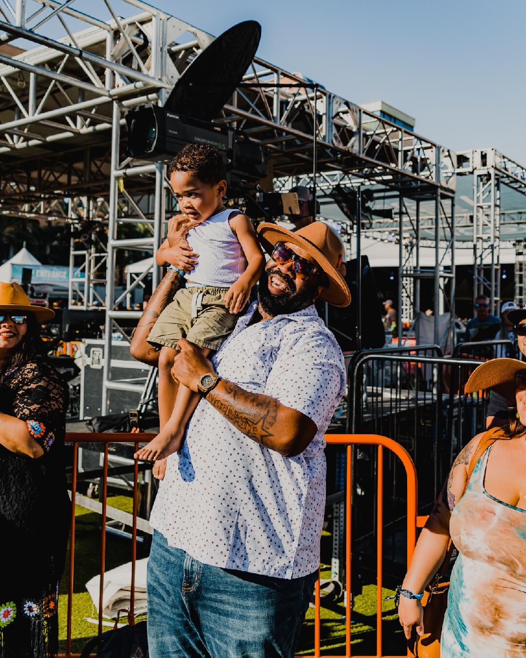 man hoists baby up in air at outdoor concert
