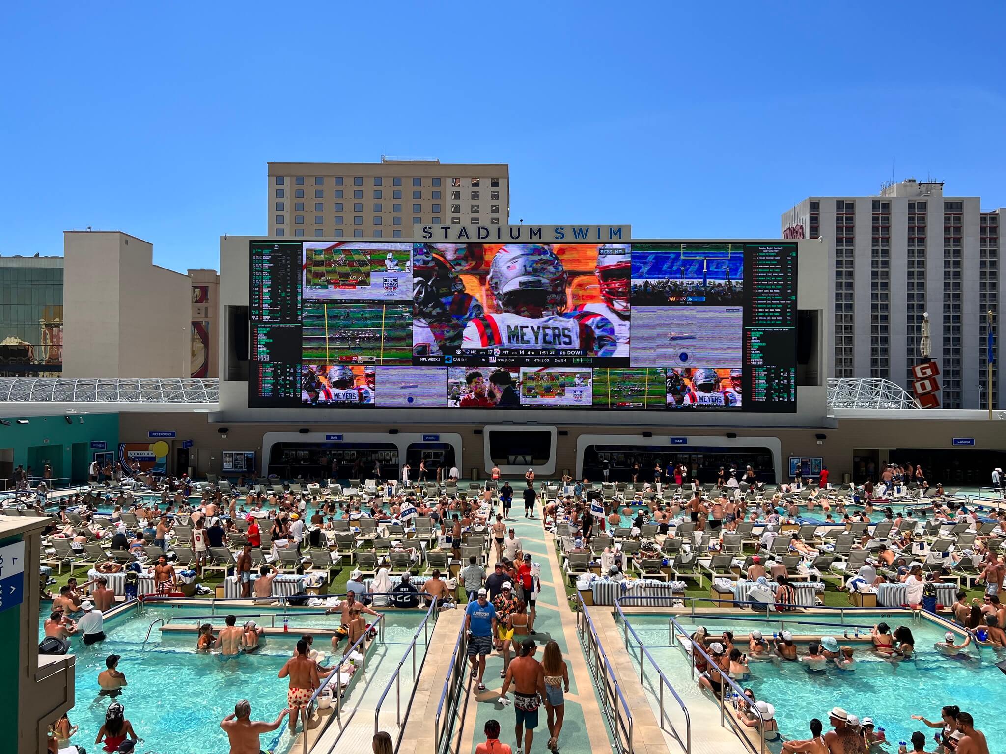 pool party attendees watch jumbo TV screens