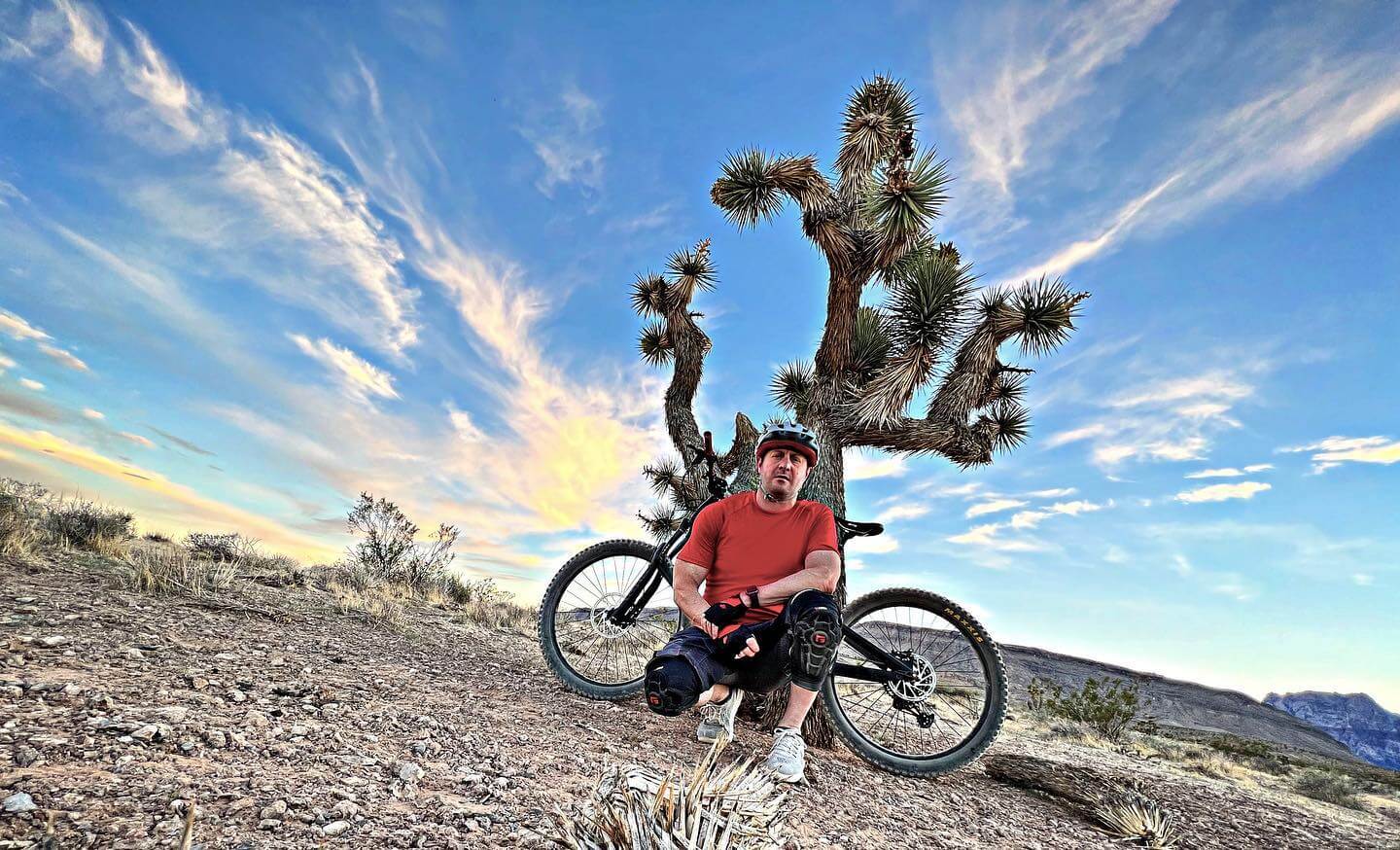 man poses with mountain bike in front of desert cactus