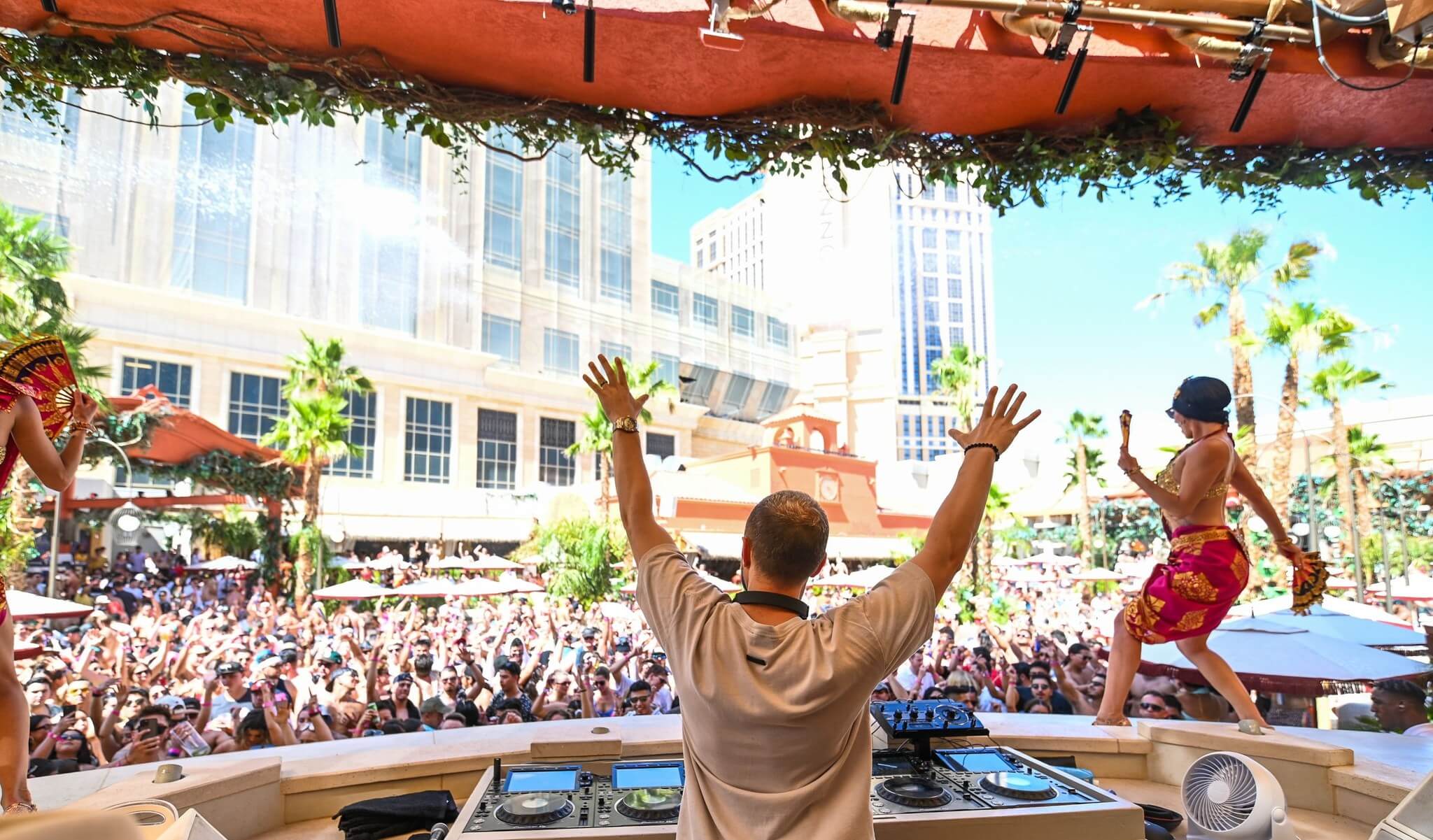 DJ raises arms to rally crowd at pool party